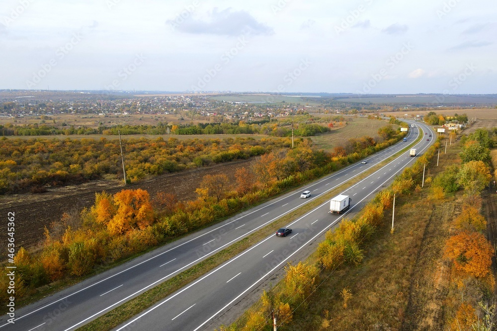 White trailer car driving on asphalt road. Road seen from air. Aerial view landscape, dron photography. Autumn highway, Ukraine