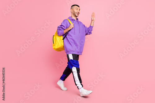 Full body photo of nice millennial brunet guy go wave wear hoodie pants shoes bag isolated on pink background