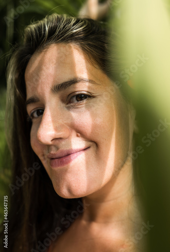 portrait of beautiful hispanic woman through palm leaves