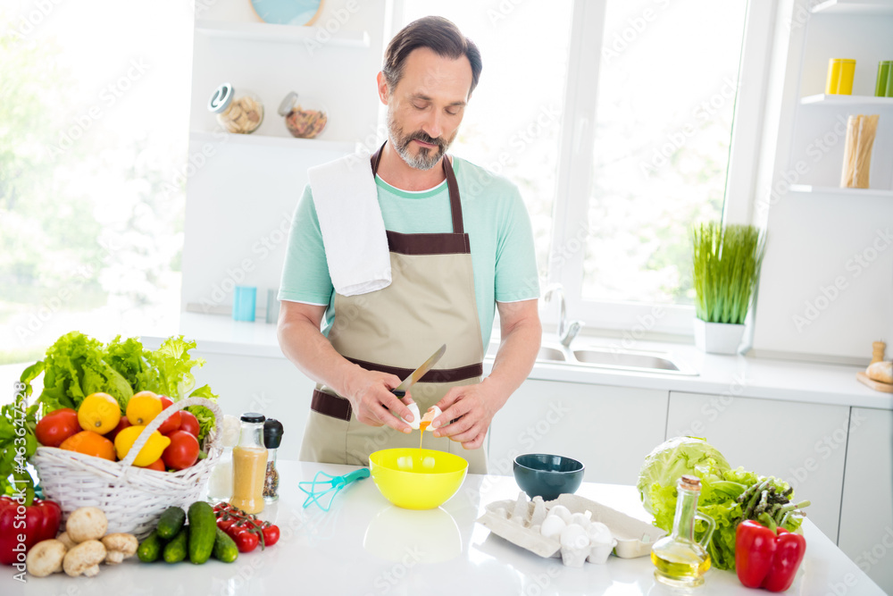 Photo of calm confident man make omelette desk table towel shoulder wear apron blue t-shirt home kitchen indoors