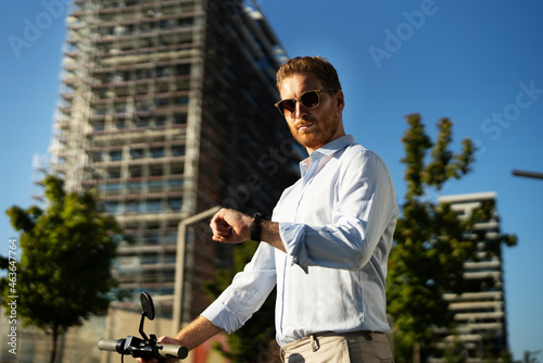 Young businessman with bicycle. Handsome man watching at wristwatch