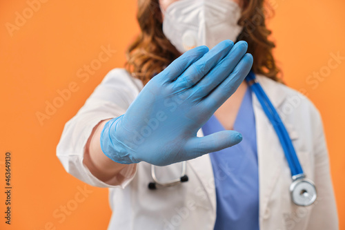 Hand of a medic in a sign of prohibition. Close-up of a doctor in protective gloves and a medical uniform photo