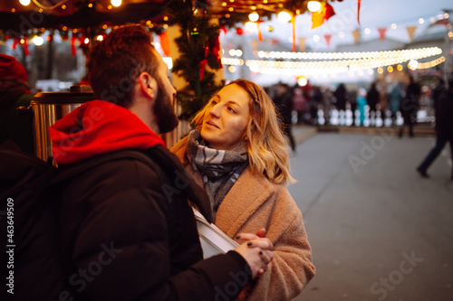 Happy couple of tourists in warm clothes walking at the christmas market. Holidays, winter, christmas, new year, travel concept. 