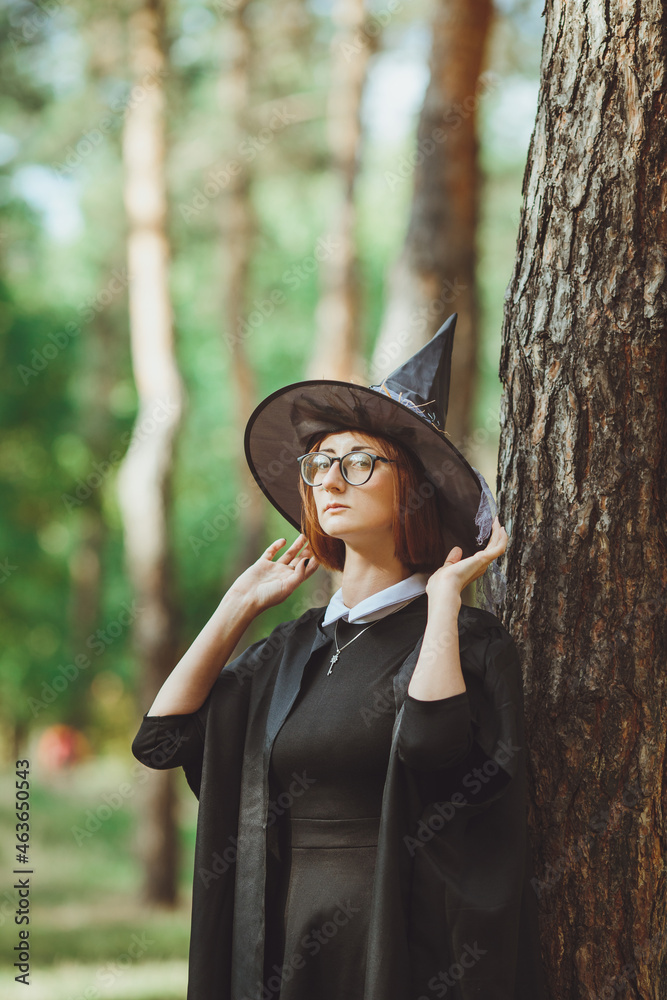 Halloween Witch. Portrait of a girl in a hat and a witch costume in the forest. Ready for trick or treat holiday