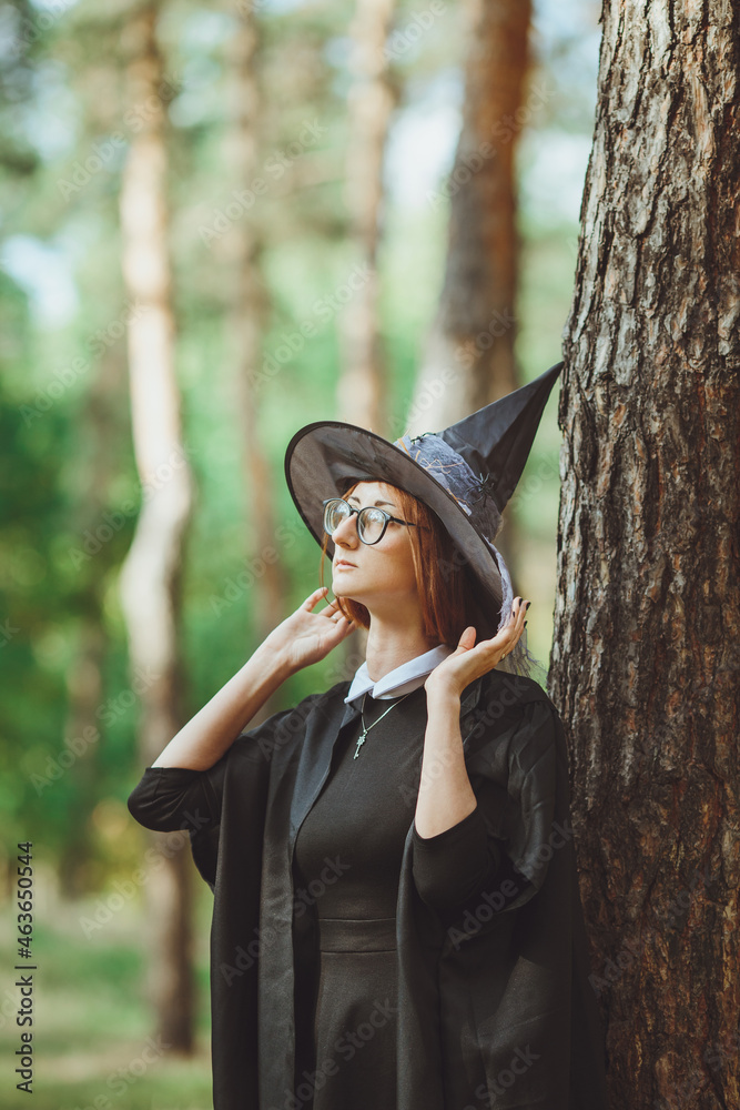 Halloween Witch. Portrait of a girl in a hat and a witch costume in the forest. Ready for trick or treat holiday