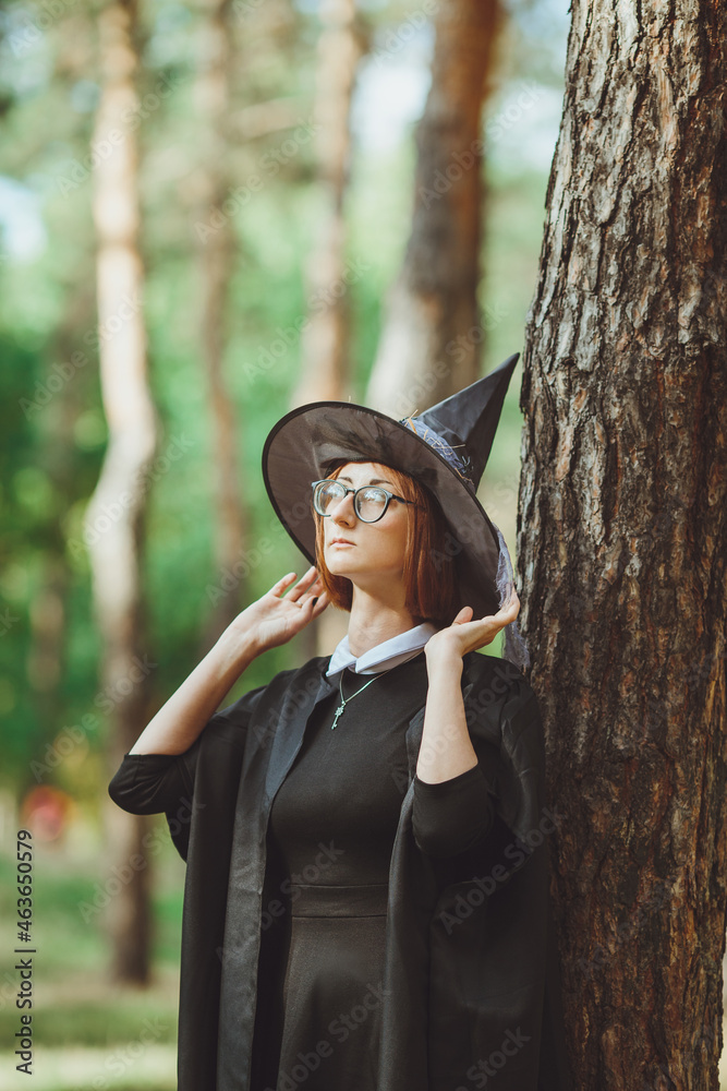 Halloween Witch. Portrait of a girl in a hat and a witch costume in the forest. Ready for trick or treat holiday