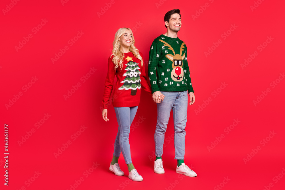 Profile photo of relaxed tourist couple hold hands walk wear ugly ornament pullover isolated red color background Profile photo of relaxed tourist couple hold hands walk wear ugly ornament pullover isolated red color background