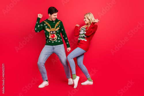 Photo of dreamy inspired couple dance have x-mas fun wear ugly sweater jeans shoes isolated red color background