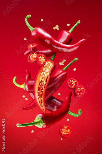 Fototapeta Fresh red chilli peppers and cross sections of chilli pepper with seeds floating in the air
