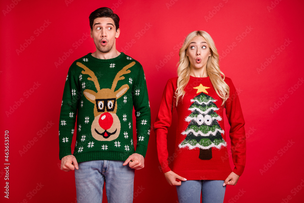 Photo portrait amazed surprised couple wearing ugly sweaters celebrating xmas isolated bright red color background