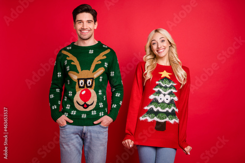 Photo portrait happy smiling couple wearing ugly sweaters celebrating winter holidays isolated vivid red color background
