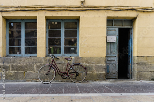 Bicycle resting on the facade of an old house with a door and two windows