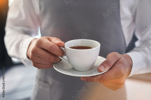 A man holds a white cup with a hot drink outdoors. A man's hand holding a mug of coffee. Close-up, image layout, place to copy text. High quality photo