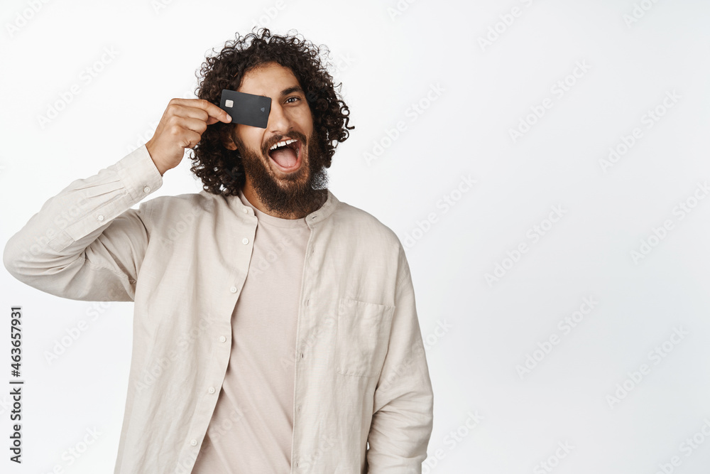 Happy hispanic guy showing credit card and smiling, recommending bank or shopping sale, white background Happy hispanic guy showing credit card and smiling, recommending bank or shopping sale, white background