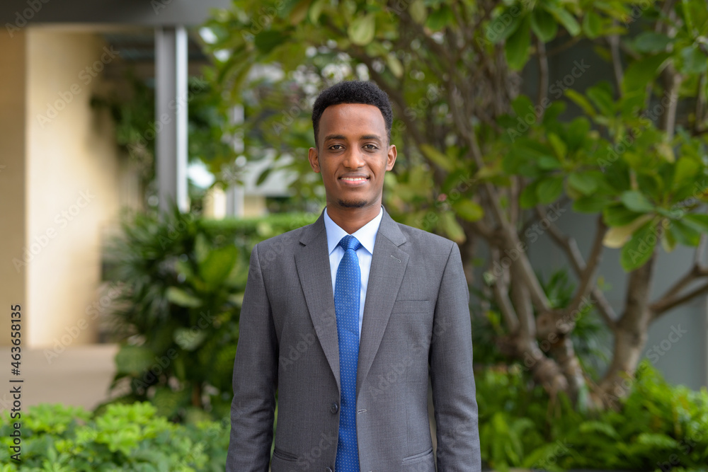 Portrait of handsome African businessman wearing suit and tie while smiling at rooftop park Portrait of handsome African businessman wearing suit and tie while smiling at rooftop park