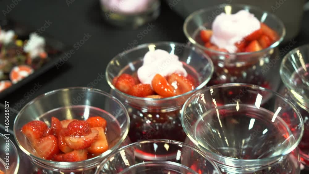 Chef lays ice cream in glass bowls with strawberries