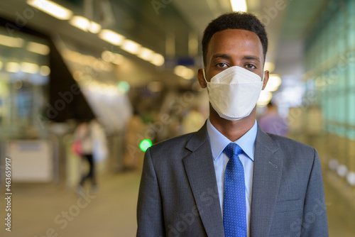 African businessman traveling in city while wearing face mask