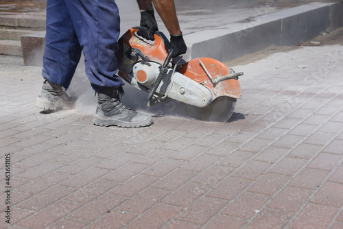 The builder works with a circular saw, cuts the laid concrete tile.