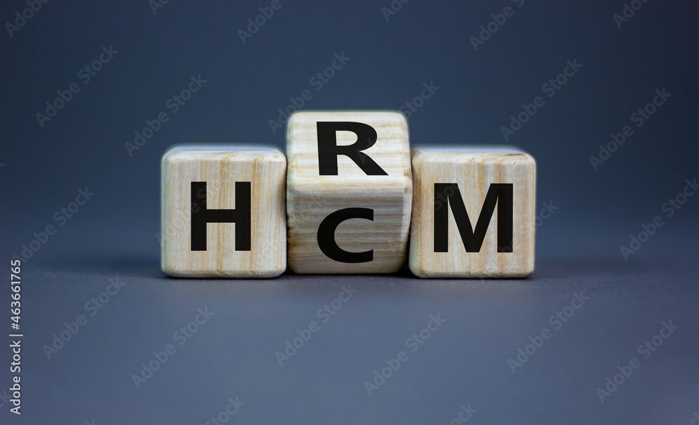 Human resource and capital management symbol. Turned wooden cubes and changed the word HCM to HRM. Beautiful grey background. Human resource and capital management and business concept. Copy space. Human resource and capital management symbol. Turned wooden cubes and changed the word HCM to HRM. Beautiful grey background. Human resource and capital management and business concept. Copy space.