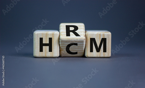 Human resource and capital management symbol. Turned wooden cubes and changed the word HCM to HRM. Beautiful grey background. Human resource and capital management and business concept. Copy space.