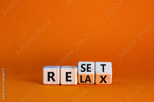 Relax and reset symbol. Businessman turned cubes and changed the word 'relax' to 'reset'. Beautiful orange table, orange background. Business, relax and reset concept. Copy space.