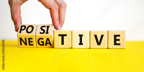 Positive or negative symbol. Businessman turns wooden cubes and changes the word 'negative' to 'positive'. Beautiful yellow table, white background. Business, positive or negative concept. Copy space.