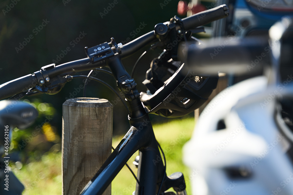 handlebars of a bicycle with helmets hanging on one side handlebars of a bicycle with helmets hanging on one side