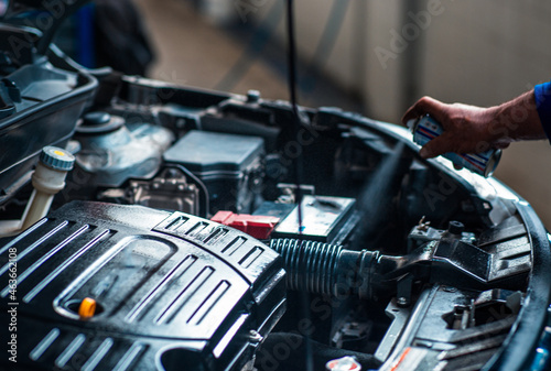 a Technician is spraying the maintenance oil to car engine photo