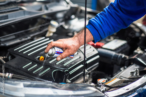 a Technician is spraying the maintenance oil to car engine
