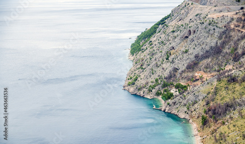 Błękitna woda morska opływająca górski stok z roślinnością strome kamieniste wybrzeże