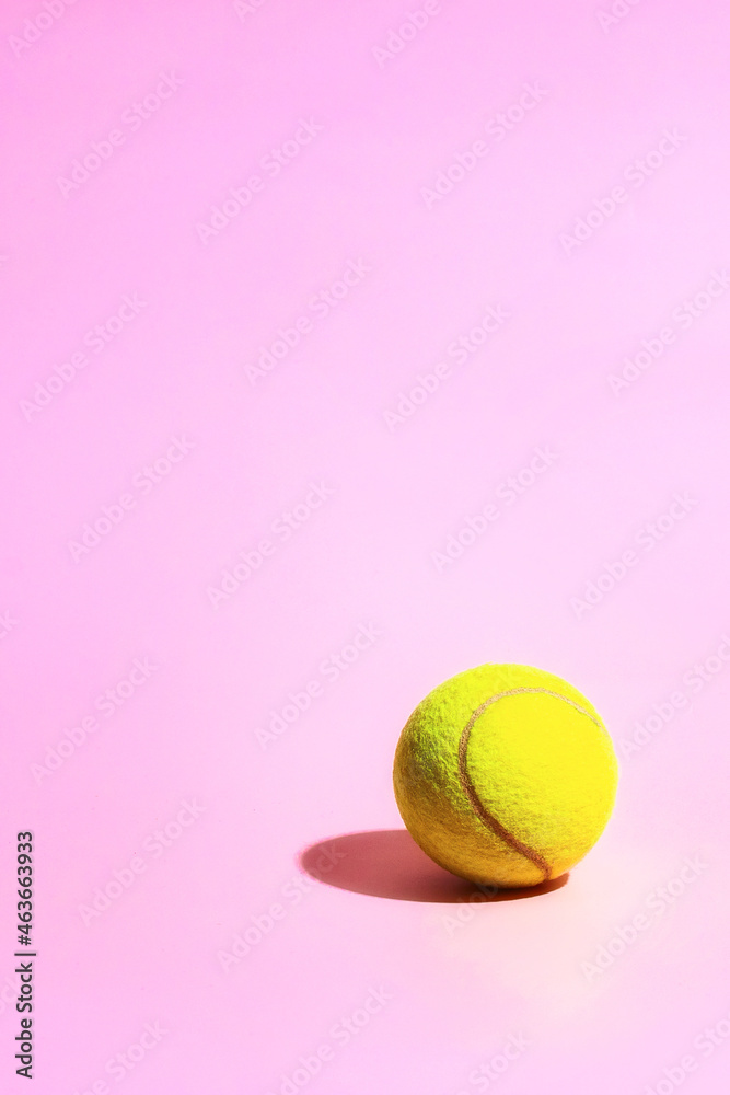 Bright yellow tennis ball on the pink background.Copy space