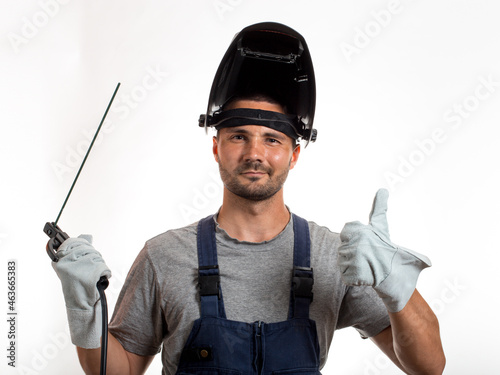 Fotografia A man with a welding mask on his head, raised up, open face, holding welding wires and an electrode in his hands
