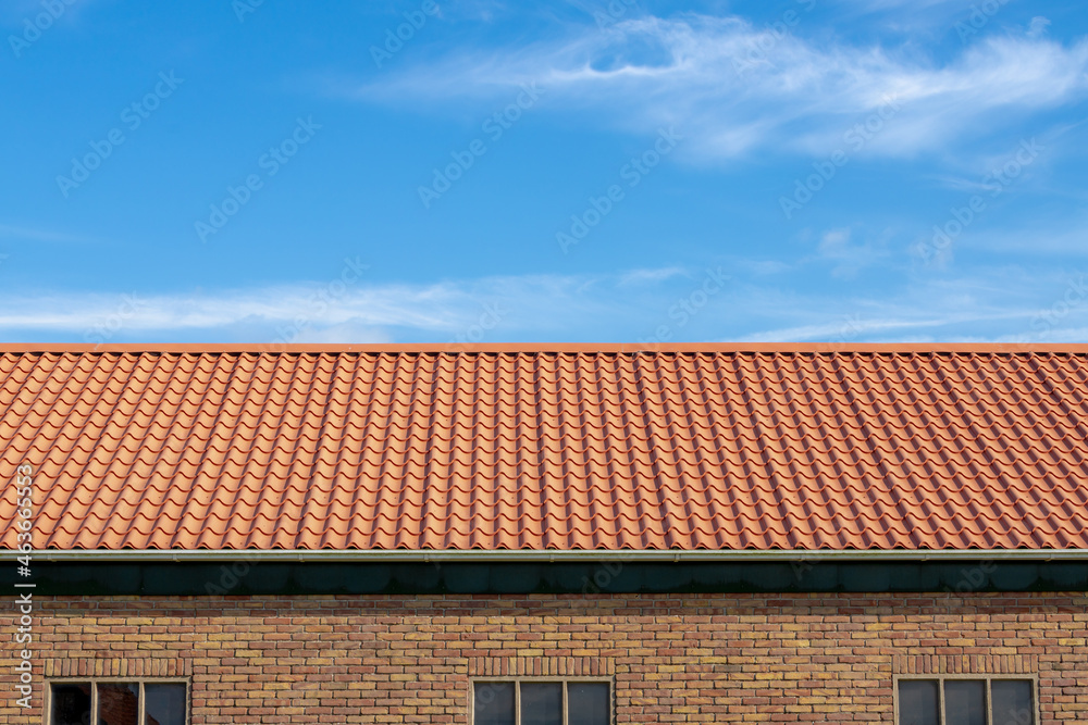 Orange brick rooftop under blue sky and white clouds, Tiles background details, Shingles texture, Abstract geometric pattern, Roof brick material and building wall. Orange brick rooftop under blue sky and white clouds, Tiles background details, Shingles texture, Abstract geometric pattern, Roof brick material and building wall.