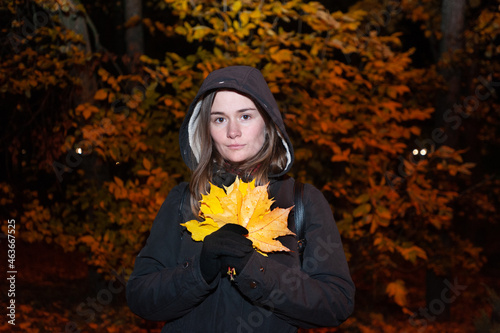 girl holding leaves in autumn night at the park