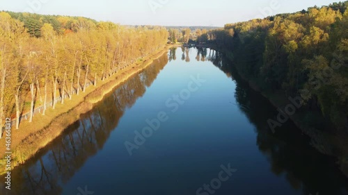 Flight over the river. On the sides are yellow trees
