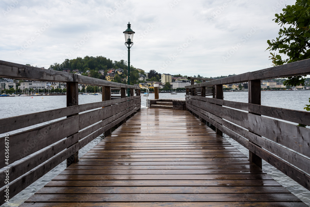 Jetty on a Traunsee lake with the town of Gmuden in the background on a rainy day,Austria