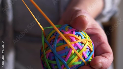 Hand stretching rubber band on colorful ball