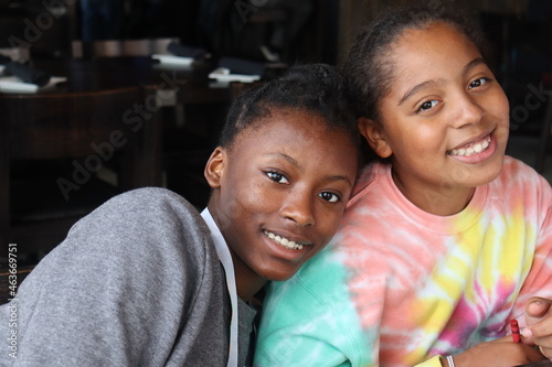 Two African American Pre Teens smiling indoors close up