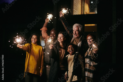 Happy big family lighting sparklers and celebrating the holiday standing outdoors