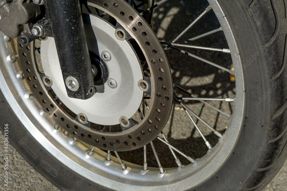 Motorcycle wheel close up. Wheel spokes. Wheel of an old motorcycle on the asphalt.