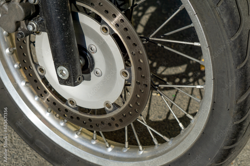 Fototapeta premium Motorcycle wheel close up. Wheel spokes. Wheel of an old motorcycle on the asphalt.
