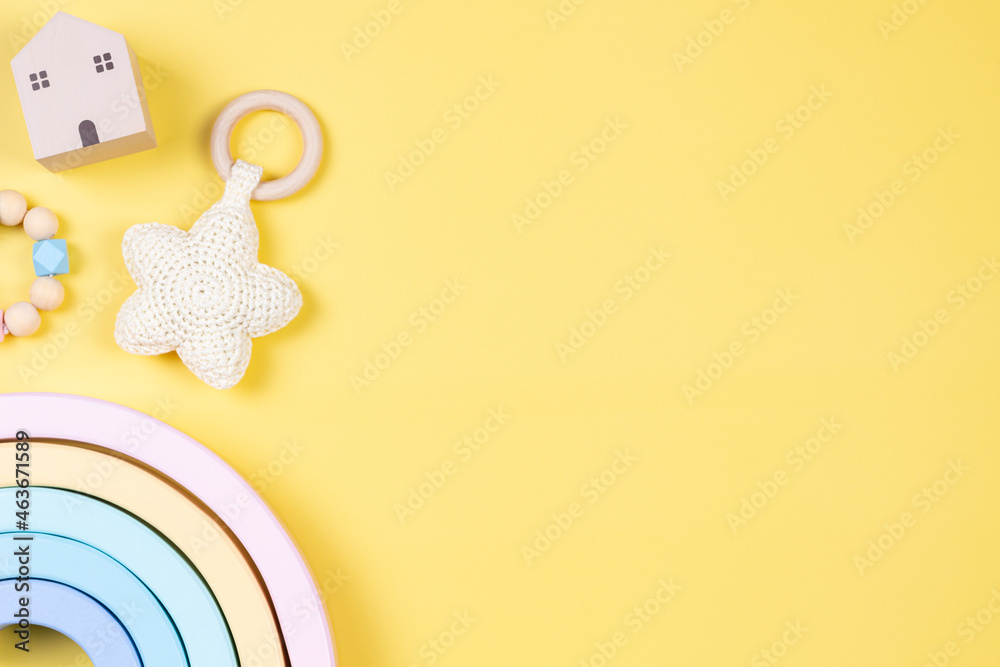 Baby kid toys on yellow background. Sustainable early childhood development baby stuff and pastel color wooden toys - obrazy, fototapety, plakaty 
