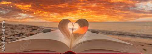 Livre plié en forme de cœur avec lever de soleil sur une plage.