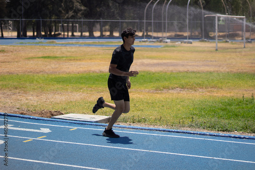 Man jogging on a blue running track  wearing black sports wear