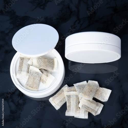 Closeup of a white swedish snus can and portion snuff pouches.