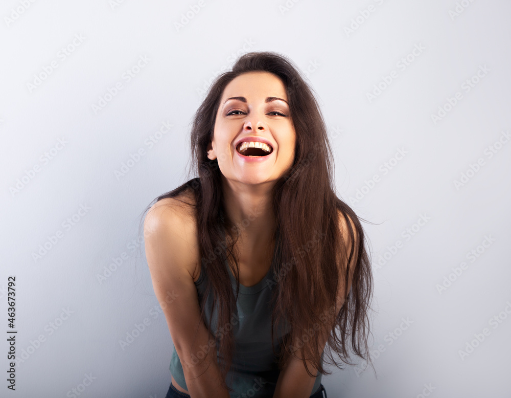Happy laughing beautiful woman covering the face the hands on blue background and happy looking in green t-shirt. Portrait Happy laughing beautiful woman covering the face the hands on blue background and happy looking in green t-shirt. Portrait