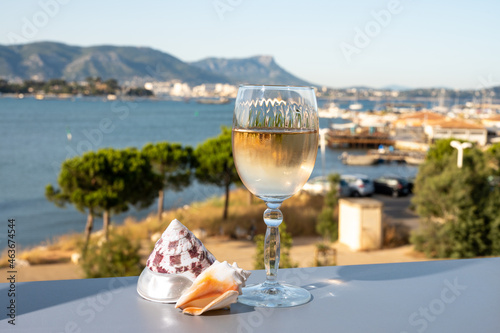 Summer on French Riviera, drinking of cold white or gris rose wine from Cotes de Provence on outdoor terrase with view on harbour of Toulon, Var, France and sea shells