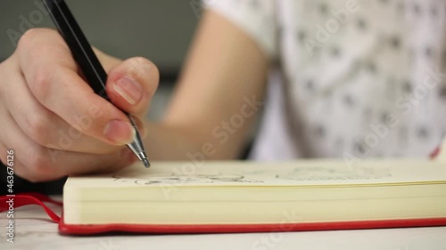 Close-up view of woman hands drawing on white paper of art book notebook with pencil. Art creation, creativity, education and learing lessons concept