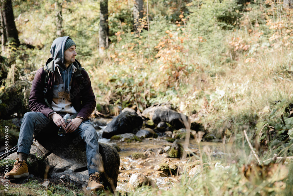 Fototapeta premium Male hiker is traveling at the mountains with backpacks exploring beautiful places of the natural park enjoying the outstanding landscape views.