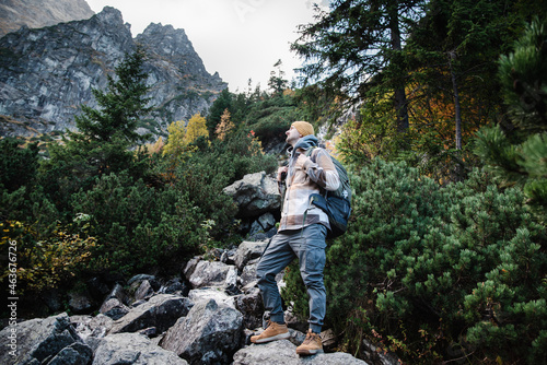 Male hiker is traveling at the mountains with backpacks exploring beautiful places of the natural park enjoying the outstanding landscape views.